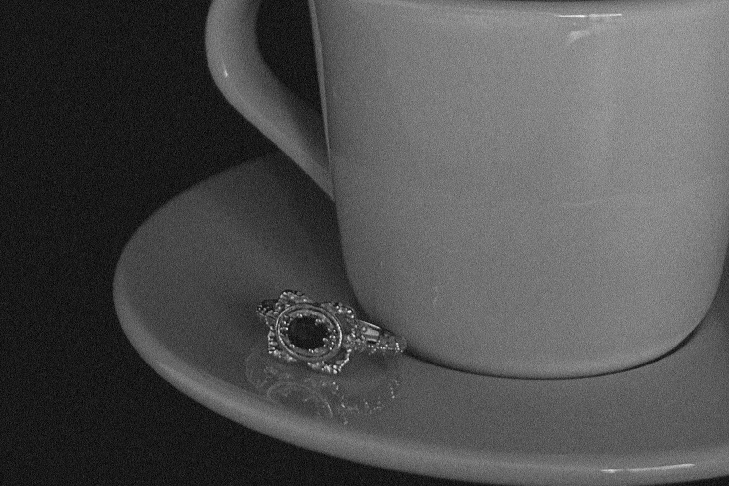 Gray cup and saucer with a ring on a black background